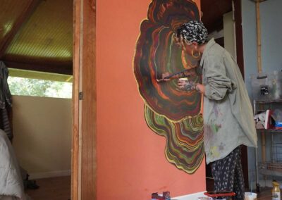 Artist resident Lottie paints a turkey tail mushroom mural in Hale Jungle