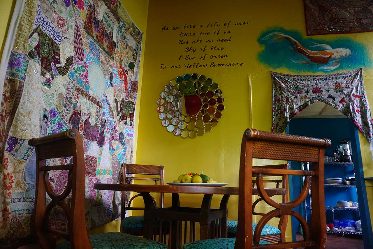 Close up of a wall in the Community Kitchen showing a hanging quilt and paintings at Earthsong Foundation Hawaii