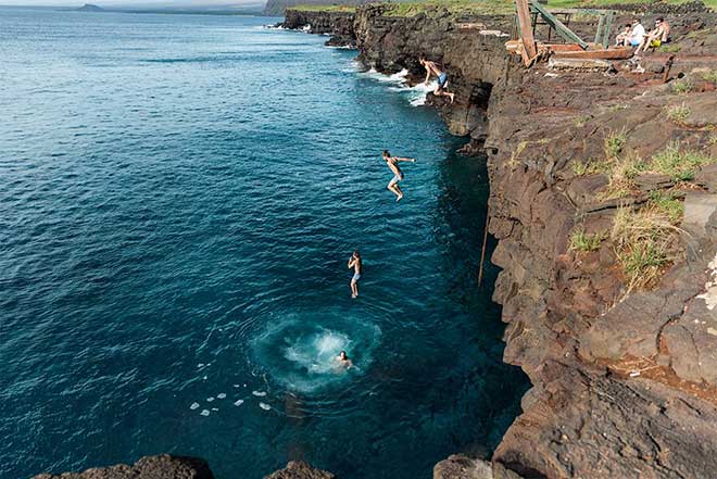 Adults jumping from a cliff into the ocean in Hawaii. Earthsong Foundation Hawaii
